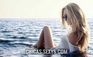 Chicas sexy: Mujer en la playa Chicas sexy: En la imagen vemos a una mujer disfrutando un día de playa. Esta sentada, mejor dicho, acostada en la orilla. No lleva un traje de baño, sino una blusa blanca. Unos lentes de sol ocultan su mirada. La pose es muy sensual, por lo que corresponde a nuestro ideal de mujer hermosa.