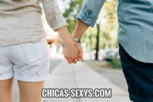Manual de seducción: Una pareja sosteniéndose de la mano y caminando por una ciudad. Lo único que se puede ver son las manos de ambos. Es una pareja feliz, contenta y exitosa. 